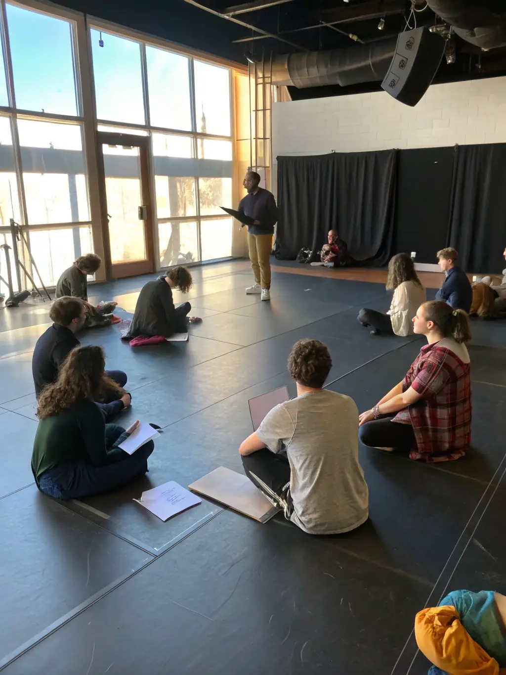 A group of participants actively engaged in a theatre workshop, learning acting techniques and stage presence from an instructor. The image should highlight the interactive and educational nature of MTM's workshops.